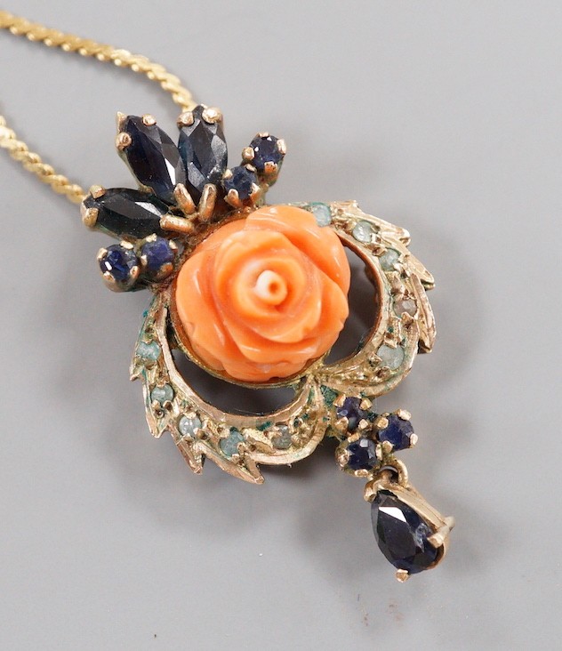 A 20th century yellow metal, carved coral, sapphire and gen set drop pendant, 32mm, on a later 750 chain, 38cm, gross weight 7.9 grams.